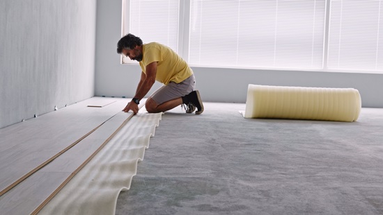 man zit op knieen om vloer te isoleren